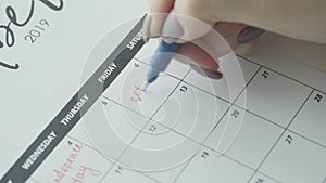 Woman`s hand writing with red felt pen on calendar word SEX