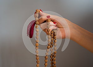 A woman`s hande holding rudraksha beads rosary on the blue background with copy space