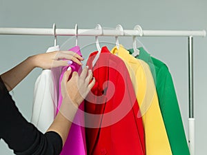 A woman's hands chooses clothes on a hanger on a white background