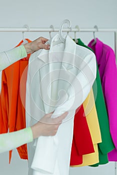 A woman's hands chooses clothes on a hanger on a white background