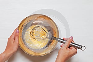 Woman`s hands close-up mixing eggs and sugar with wisk in a bowl