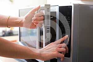 Woman`s Hands Closing Microwave Oven Door And Preparing Food in
