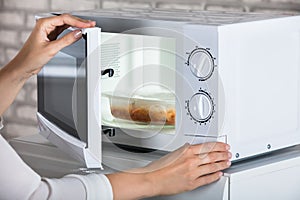 Woman`s Hands Closing Microwave Oven Door And Preparing Food