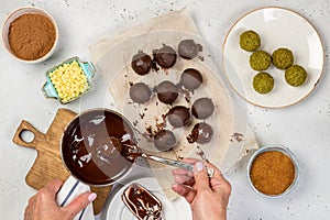 Woman`s hands cover candy with tempered chocolate.