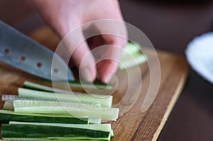 Woman& x27;s Hands Cut Cucumber Matchsticks with Santoku Knife on a Wooden Chopping Board. Salads, Maki and Temaki Sushi Rolls