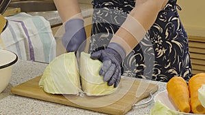 Woman\'s hands cut a head of cabbage into pieces for shredding into strips.