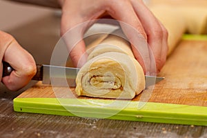 Woman`s hands cut the roll of dough. Pastry chef cuts the rolls of dough. The process of making buns