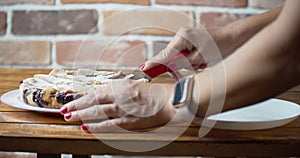 Woman`s hands is cutting bilberries pie