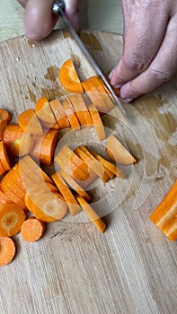 Woman\'s hands cutting carrots on the table. vertical videos