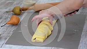 Woman`s hands cutting homemade pear cinnamon roll dough. A step-by-step recipe for sweet cinnamon rolls.