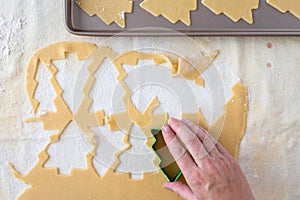 WomanÃ¢â¬â¢s hands cutting out Christmas tree sugar cookies, pastry cloth, cookie sheet