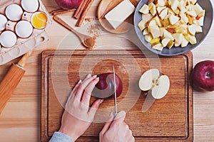 Woman`s hands cutting red apple on the table