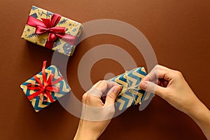 Woman`s hands decorate present box on paper background. New Year, holidays and celebration decorations concept