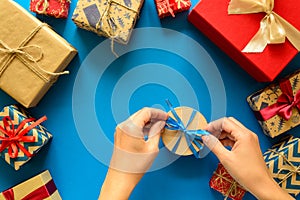 Woman`s hands decorate present box on paper background. New Year, holidays and celebration decorations concept.