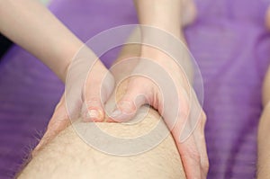 Woman`s hands doing leg massage to a man. Rehabilitation doctor massages legs after injury