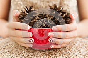 Woman& x27;s hands with french manicure and candy cane pattern on the nails. Woman with beautiful manicure holding big