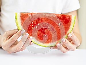 Woman`s Hands with French Manicure on Nails Holding a Slice of Fresh Watermelon. Summer concept