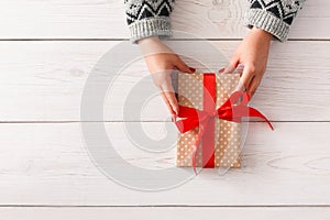 Woman`s hands give christmas gift in present box