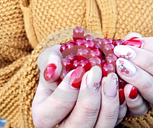 A woman`s hands hold a bright viburnum against a knitted sweater, close - up-the concept of the usefulness of using a medicinal