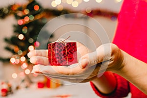 Woman`s hands hold christmas or new year decorated gift box. Selective focus