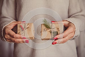 Woman`s hands hold christmas or new year decorated gift box. Ton