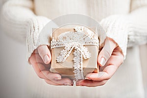 Woman`s hands hold christmas or new year decorated gift box, vintage rustic style. close up