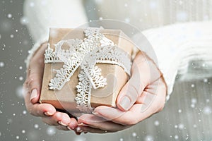 Woman`s hands hold christmas or new year decorated gift box, vintage rustic style. close up