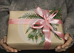 Woman`s hands hold christmas or new year giftbox with pink ribbon. Toned picture.