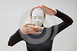 Woman`s hands hold gypsum mask. Girl in a black jumper with plaster sculpture on a white background. Concept The masks