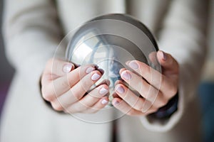 Woman`s hands hold metal ball in palms, classic manicure powdery color