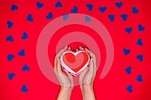 Woman`s hands hold red heart on red background