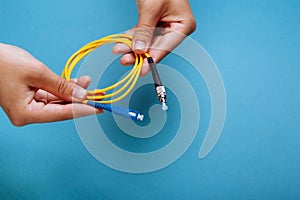 woman& x27;s hands hold SC and FC connector fiber optic patch cord single mode on blue background