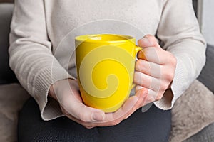 Woman's hands hold a yellow clean mug, providing a flawless surface