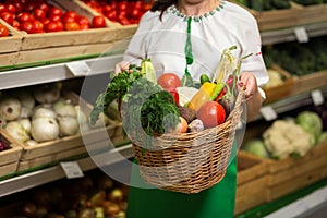 Woman`s hands holding a basket of vegetables harvest in market