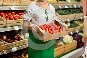 Woman`s hands holding a big box of tomato harvest in market