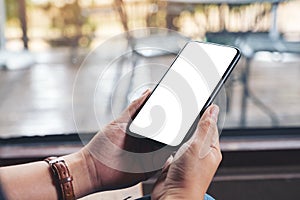 Woman`s hands holding black mobile phone with blank desktop screen