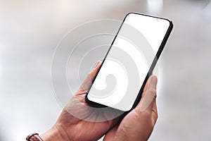 Woman`s hands holding black mobile phone with blank desktop screen