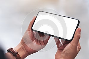 Woman`s hands holding black mobile phone with blank desktop screen