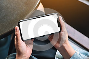 A woman`s hands holding black mobile phone with blank desktop screen