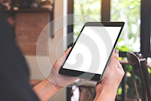 Woman`s hands holding black tablet pc with blank desktop screen in cafe