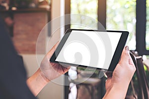 Woman`s hands holding black tablet pc with blank desktop screen in cafe