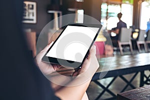 Woman`s hands holding black tablet pc with white blank desktop screen in cafe