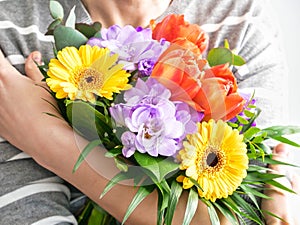 woman& x27;s hands holding a bouquet of colorful flowers. mothers day or womens day background. Gift and present concept.