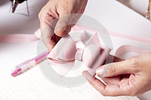 Woman`s hands holding a bow made of pink leather