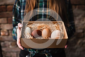 Woman`s hands holding a box of chicken eggs. Diversity of chicken eggs.