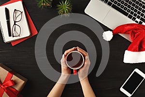 Woman`s hands holding coffee cup, top view