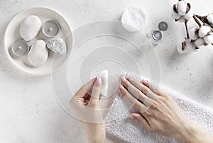 Woman`s hands holding a cotton pad and removing pink nail polish.