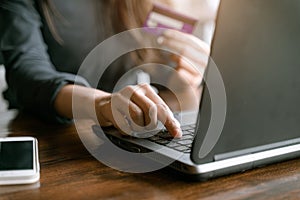 Woman`s hands holding credit card and typing on the keyboard of laptop for shopping online. Pays for purchase