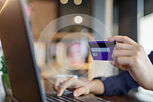 Woman`s hands holding credit card and typing on the keyboard of laptop for shopping online. Pays for purchase.