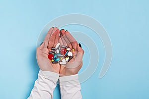 Woman`s hands holding a different tablets and pills over blue